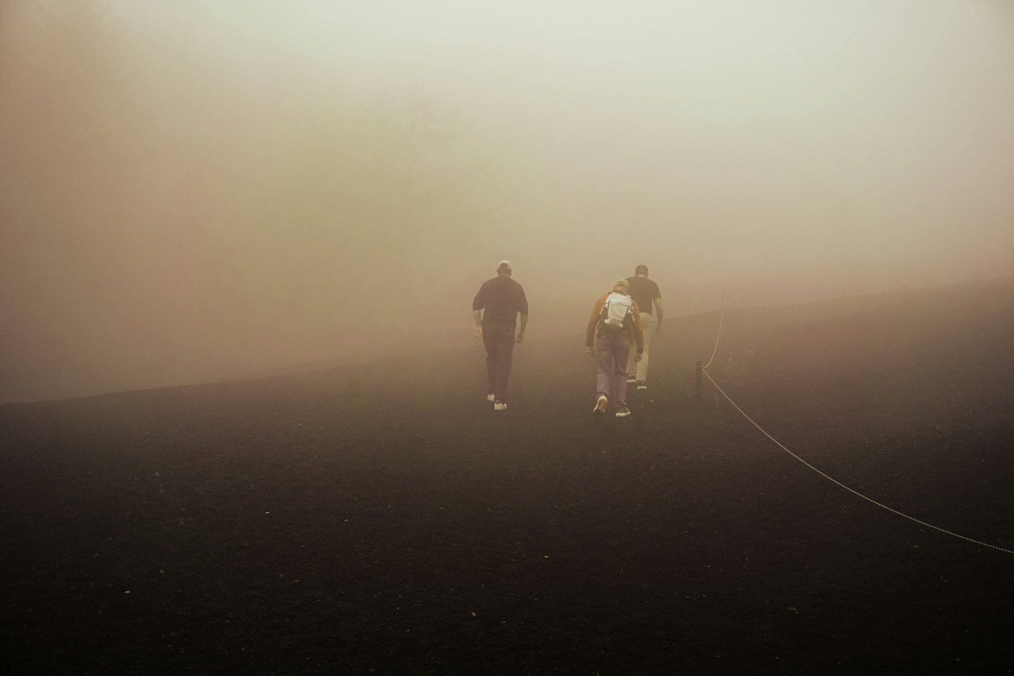 Tre escursionisti salgono un sentiero ripido nella fitta nebbia.