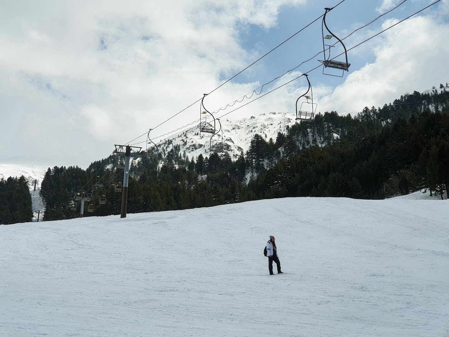 Sciatore su una pista battuta con vista sulle montagne innevate.